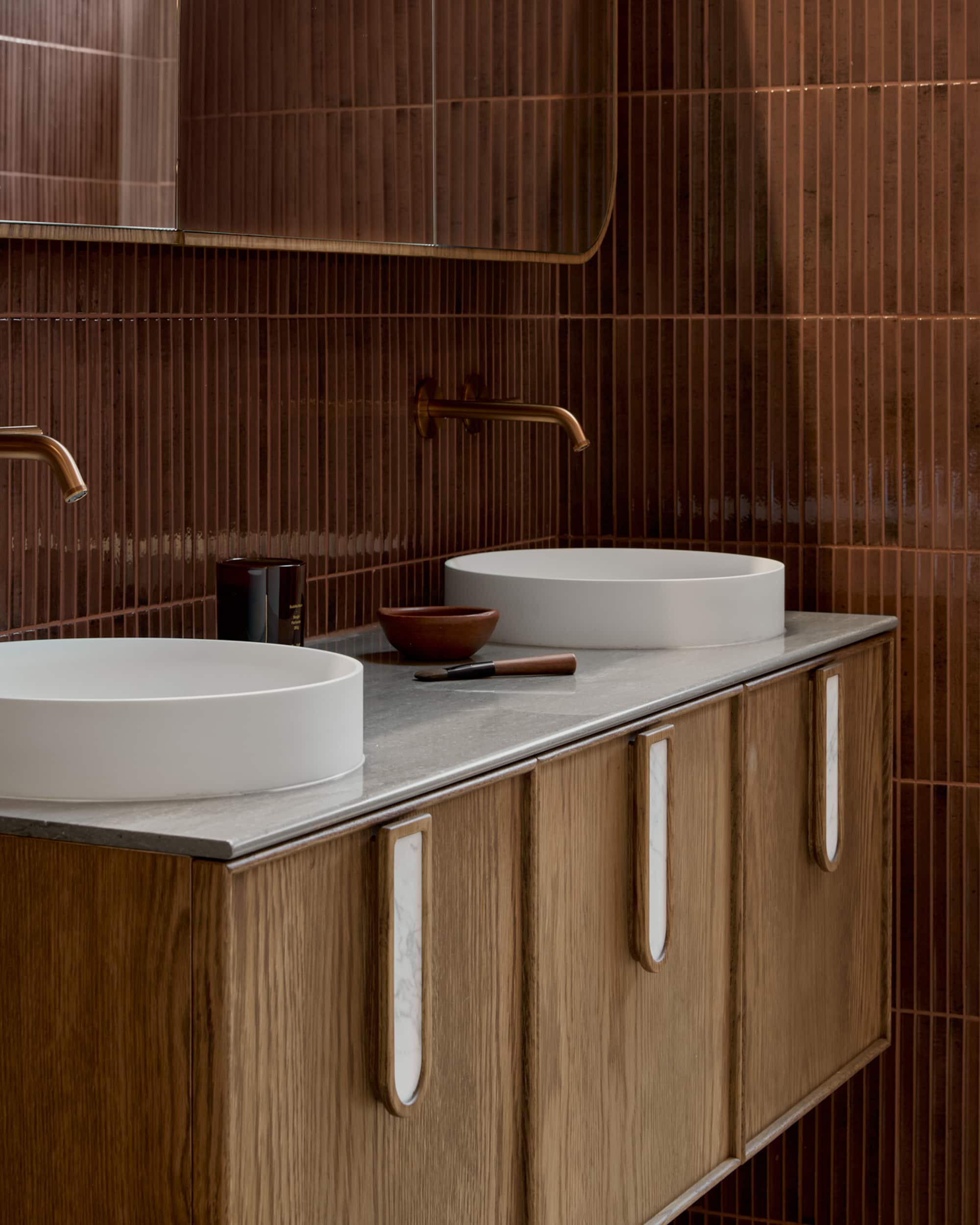 Sleek bathroom with timber vanity, dual white basins and burgundy tile walls