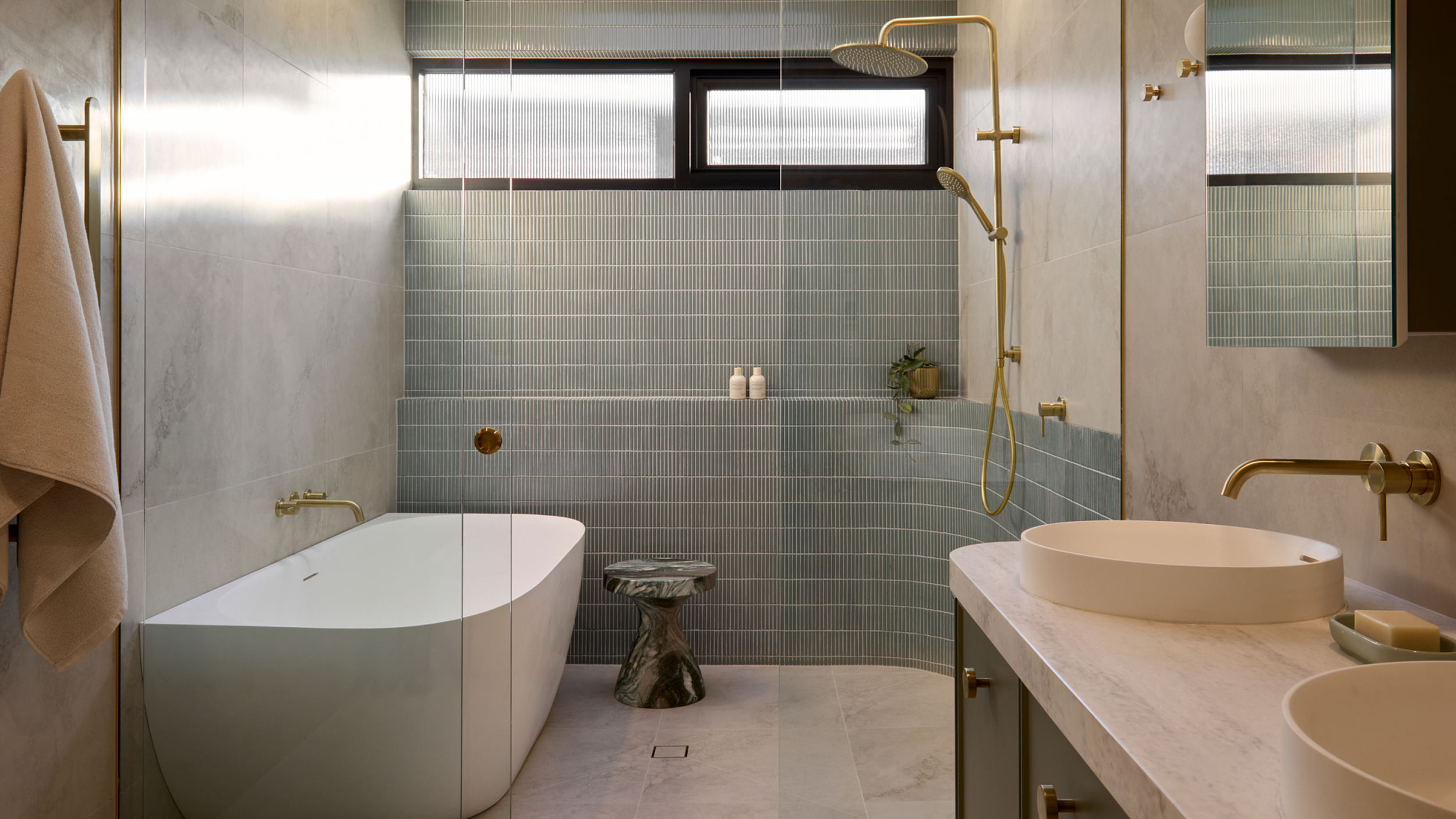 A spa-like bathroom featuring soft green tile, and a freestanding bath next to an expansive shower
