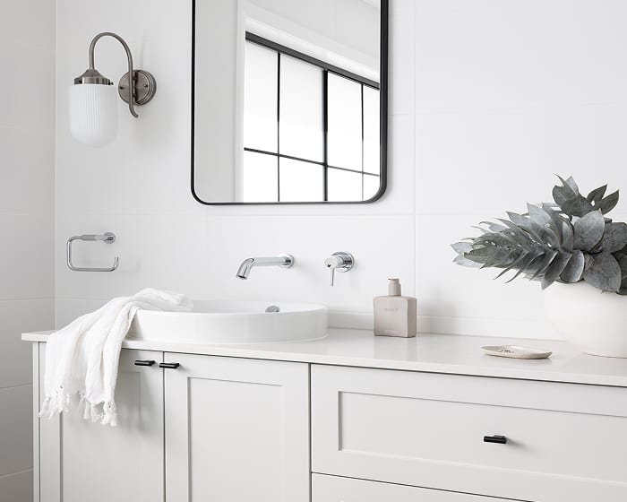 A white bathroom with a sleek semi-recessed basin, paired with a white vanity and chrome tapware, creating an elegant and airy aesthetic.