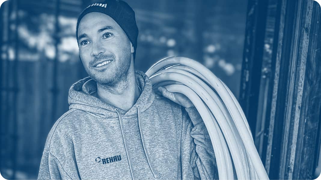 A plumber holding a coil of pipe on his shoulder