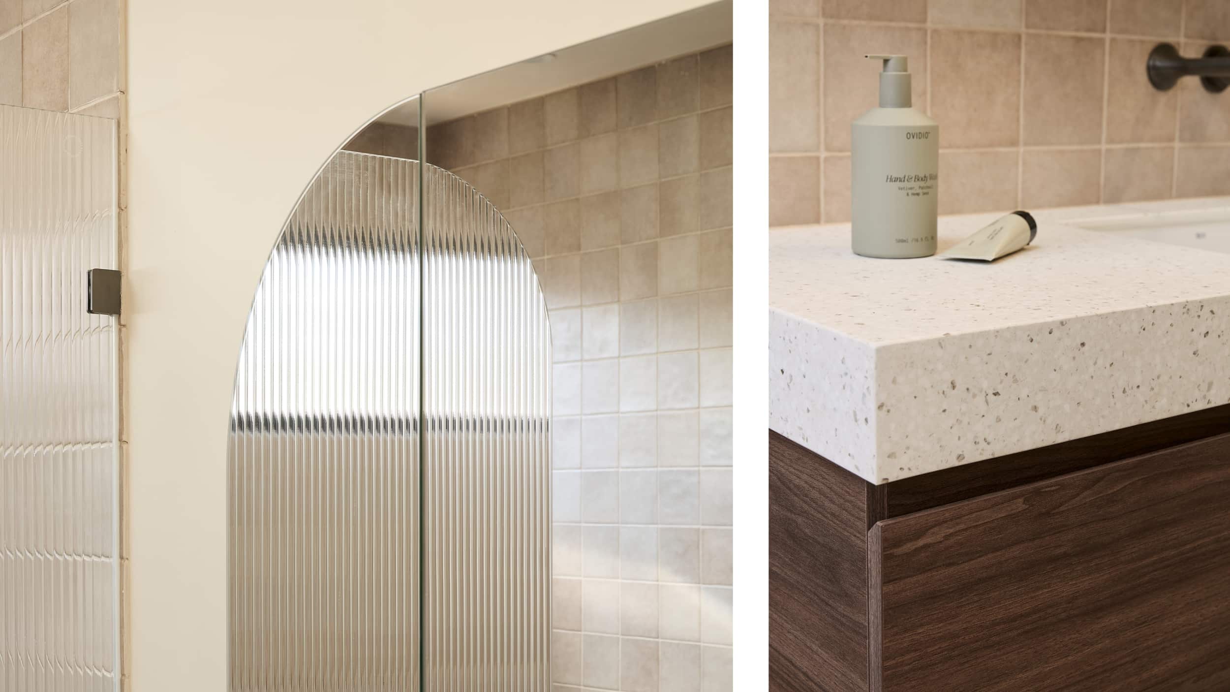 A spa-like bathroom featuring blush tile, deep walnut vanity, arched mirror cabinet which is reflecting a fluted glass shower screen