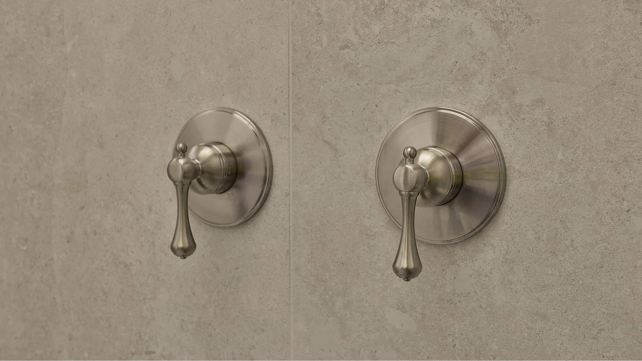 Two brushed nickel shower mixers on a neutral tile wall