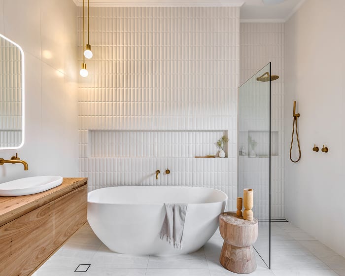 A stylish, white bathroom featuring soaking bathtub, walk in shower and wooden vanity.