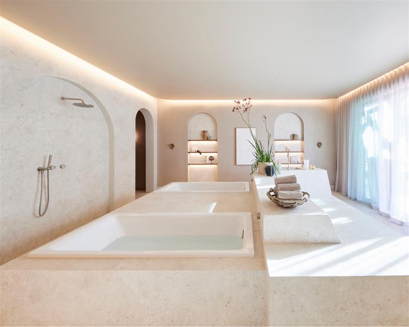 A bright and airy bathroom including bath, shower and large windows