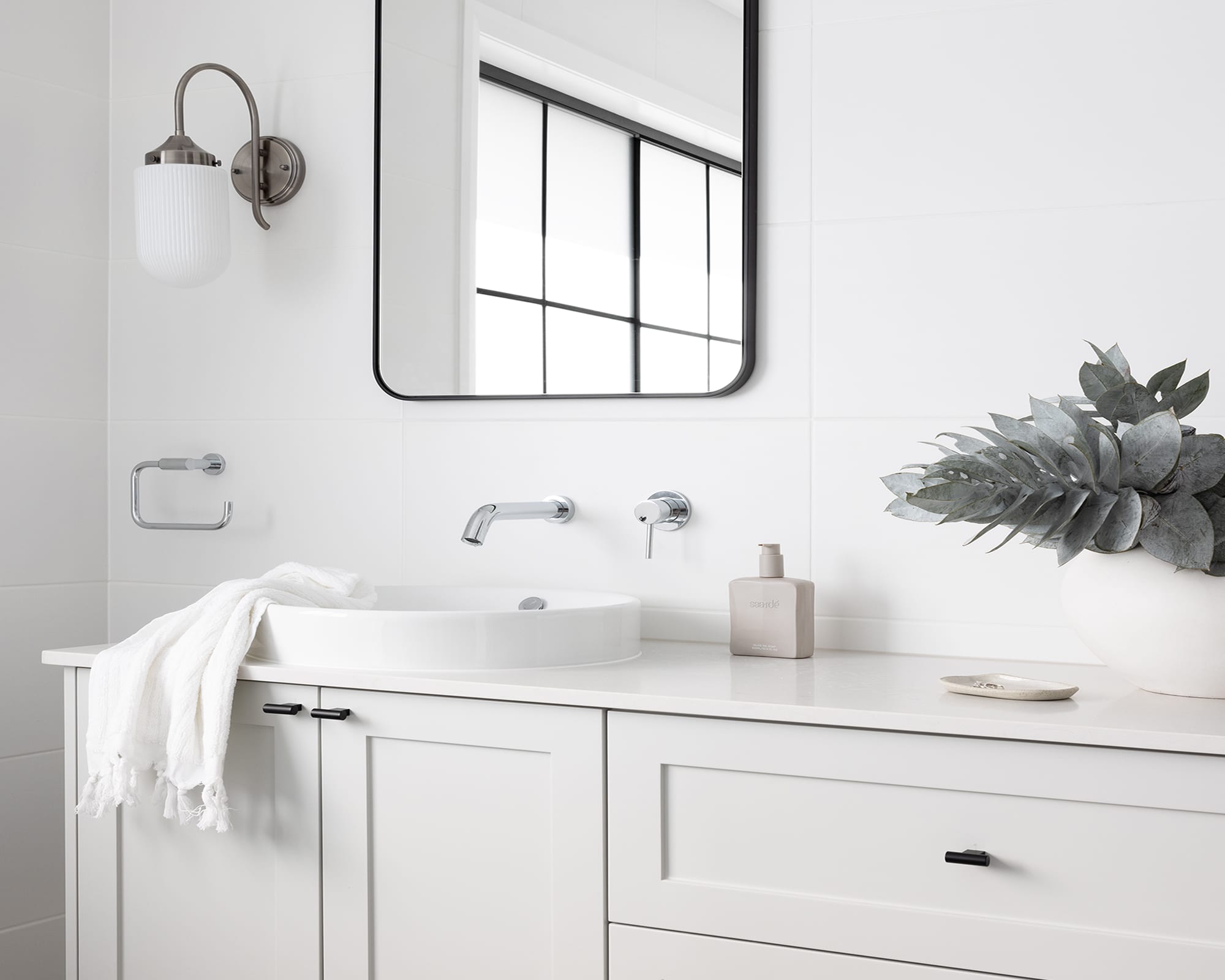 A white bathroom with a sleek semi-recessed basin, paired with a white vanity and chrome tapware, creating an elegant and airy aesthetic.