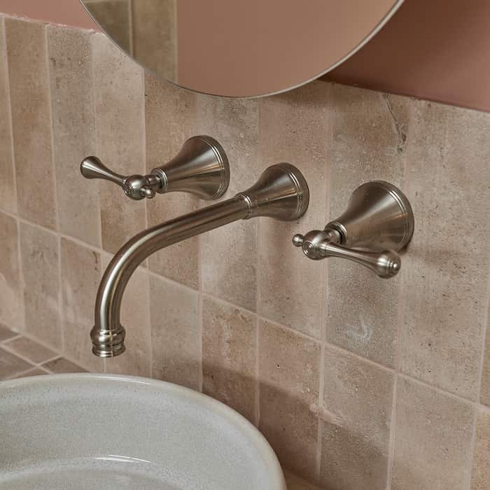 Traditional brushed gunmetal tapware on a blush-coloured tile wall