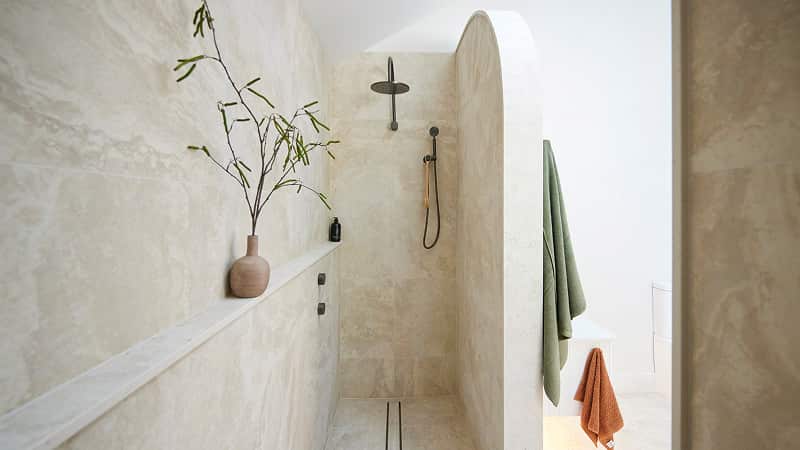 A light bathroom featuring long walk in shower and arched walls