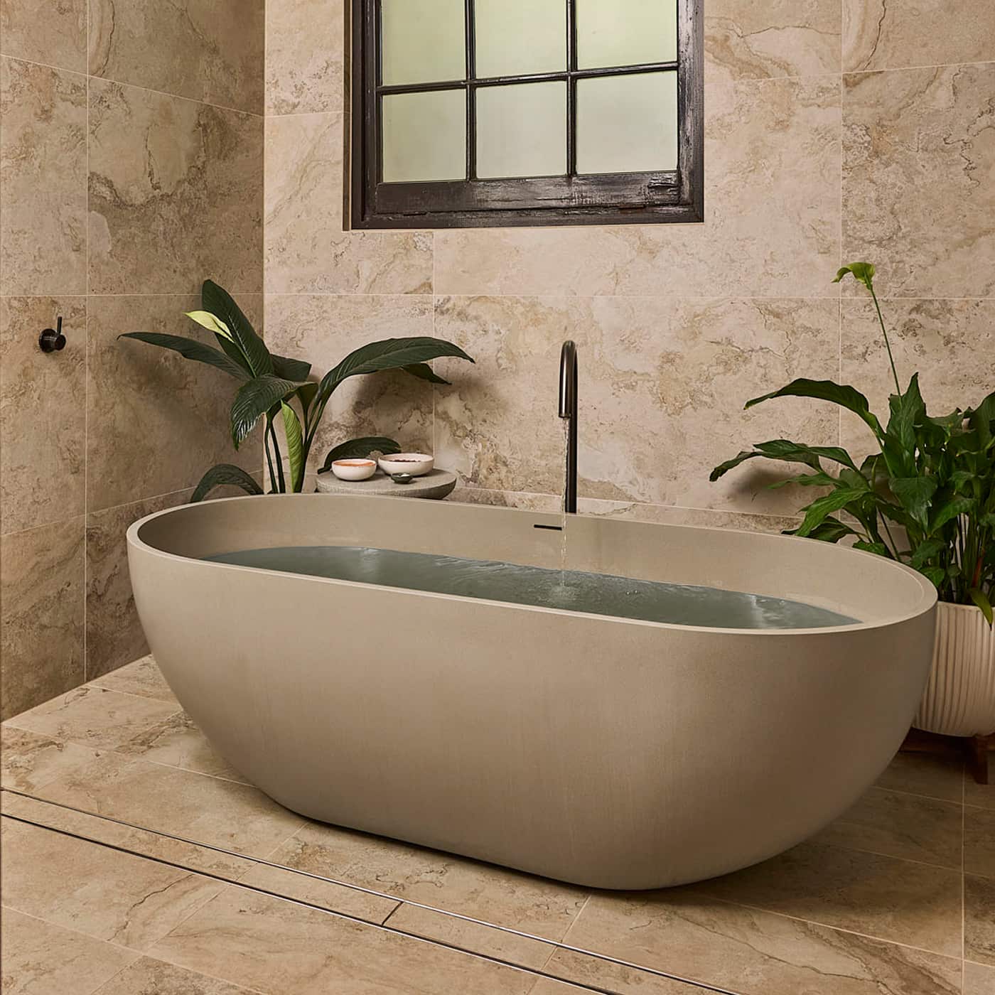 Spa-like bathroom, featuring a bathtub full of water, tiled walls and window