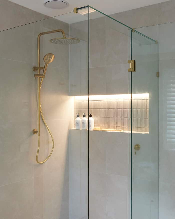 An enclosed shower with gold fixtures