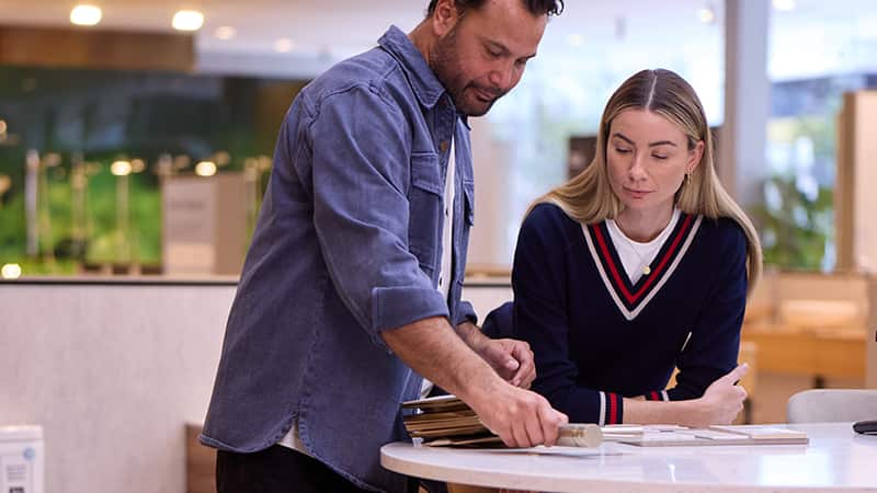 A man and a woman looking at samples while standing at a table in a bathroom showroom