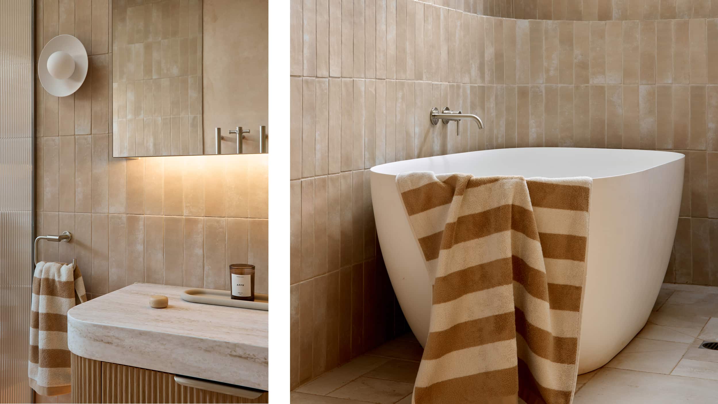 A spa-like bathroom featuring muted tile, freestanding bath, timber vanity, mirrored cabinet with LED lighting, finished with striped towels