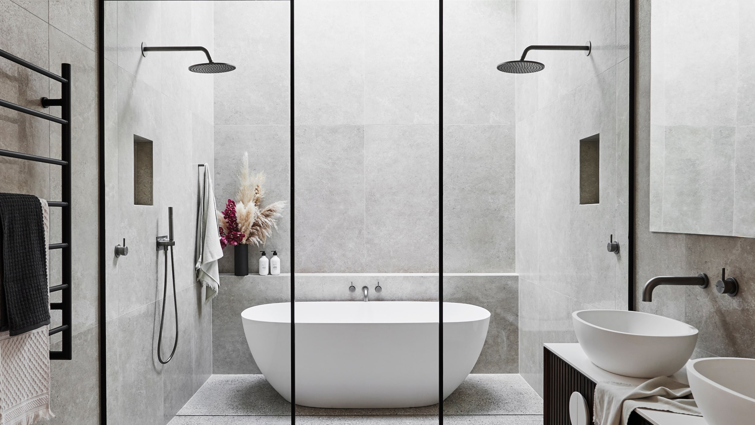 A stylish bathroom featuring expansive shower room with a central bathtub, and matte black showers on either side.
