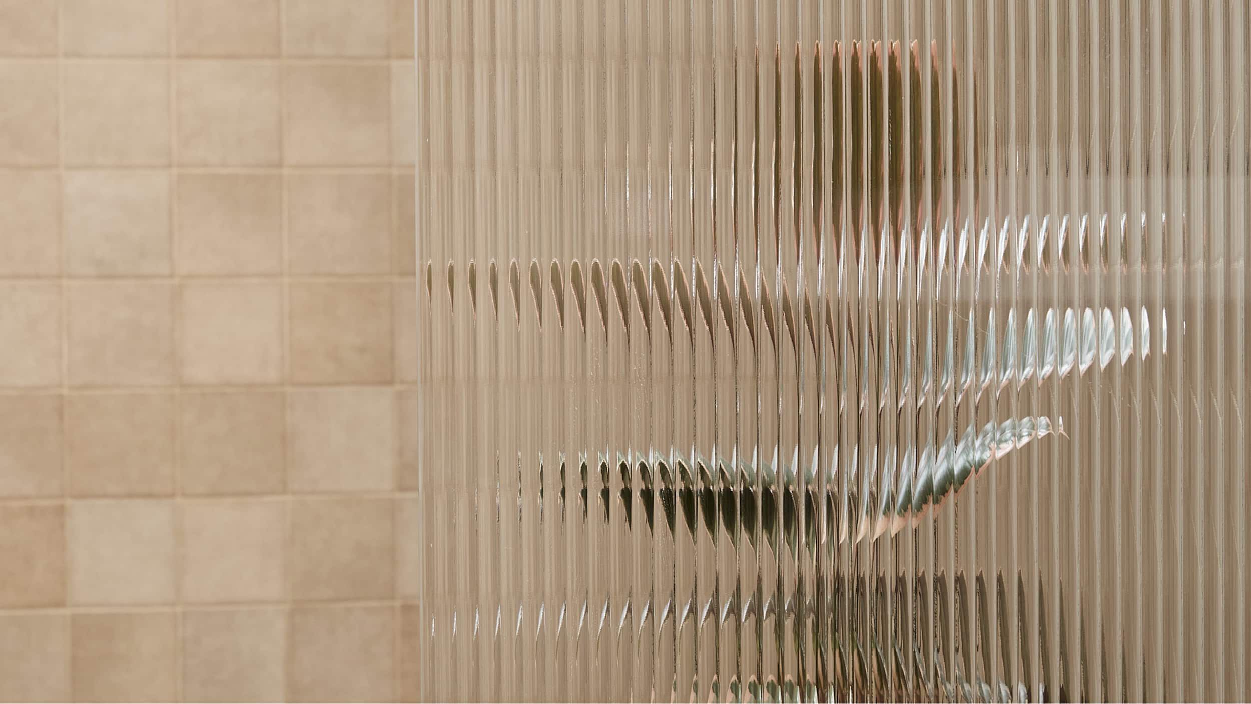 An expansive shower with blush tile, with fluted glass shower screen, which is blurring the brushed gunmetal fixtures