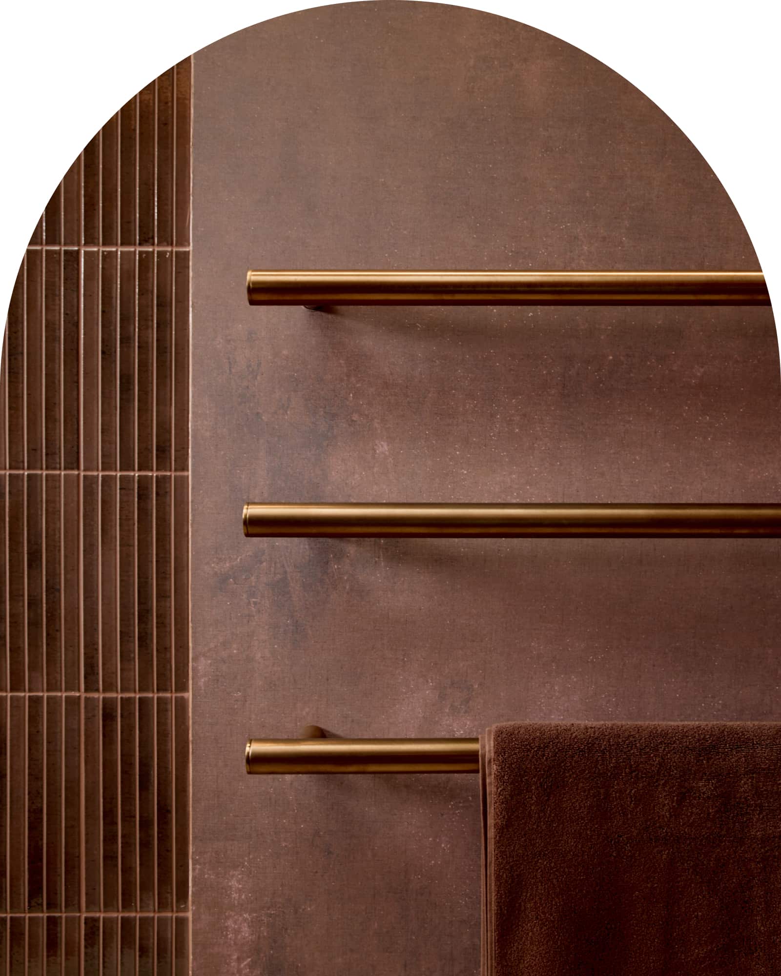 Three brushed bronze horizontal towel rails on a burgundy wall