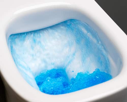A toilet, flushing with blue water