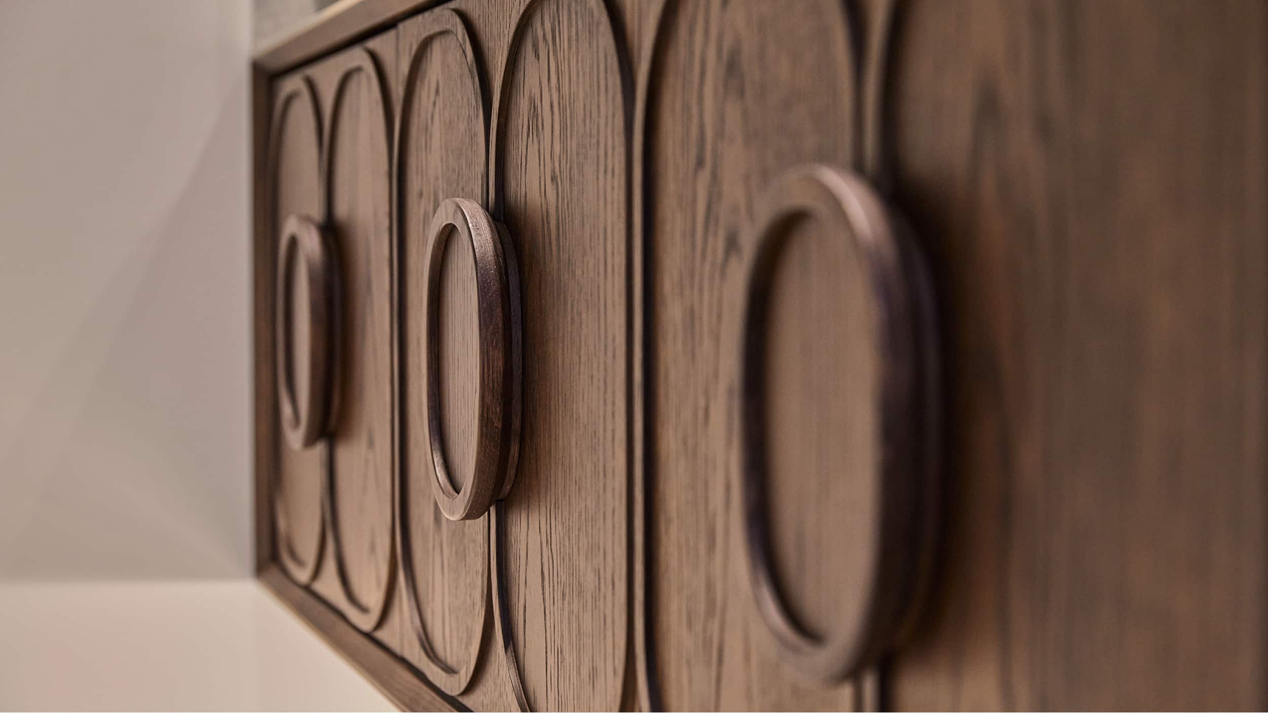 A close up of the front of an intricate walnut vanity, with oval detailing on the doors