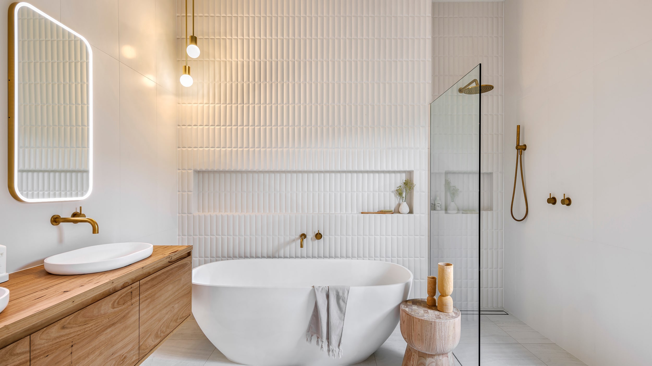 A stylish, white bathroom featuring soaking bathtub, walk in shower and wooden vanity.