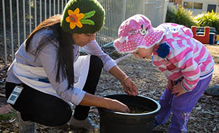 Image of educator and child gardening