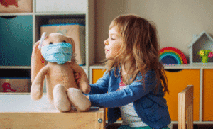 Child looking at stuffed toy with mask on